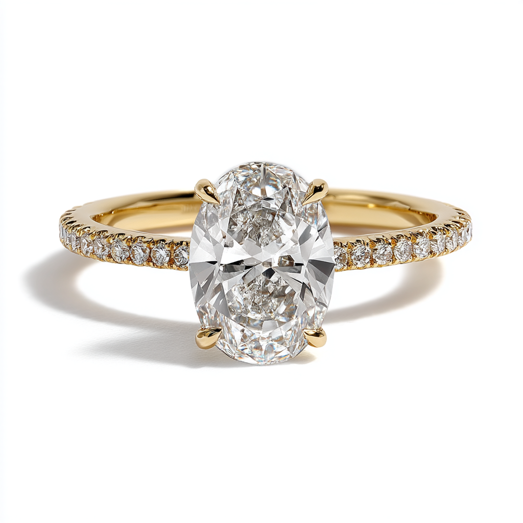 An oval-cut diamond solitaire engagement ring with a delicate pavé band in yellow gold