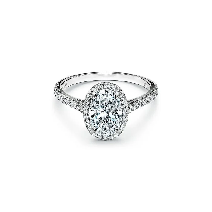 An oval diamond solitaire engagement ring on a finger